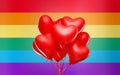 Red heart shaped helium balloons over rainbow flag
