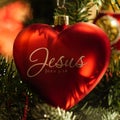 Red heart shaped Jesus Christmas ornament on tree
