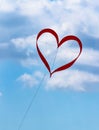 Red heart shaped kite flying in blue sky Royalty Free Stock Photo