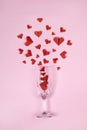 Red heart shaped paper origami explode from champagne glass on pink background for Valentine`s day poster Royalty Free Stock Photo