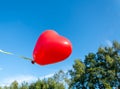 Red heart shaped party balloon floating in air