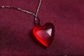 Red heart-shaped pendant on leather fabric Royalty Free Stock Photo