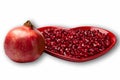 Red heart shaped plate full of delicious ripe juicy pomegranate seeds whole fruit and white background Royalty Free Stock Photo