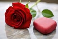 a red heart-shaped stone balanced on a petal of a rose