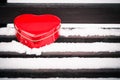 Red heart shaped tin box on a bench covered with snow Royalty Free Stock Photo