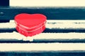 Red heart shaped tin box on a bench covered with snow Royalty Free Stock Photo