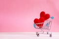 The red Heart shapes in shopping cart on sweet pink background , the love concept for shopping on valentines day with sweet and