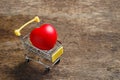 Red heart in shopping cart on wooden table. Royalty Free Stock Photo