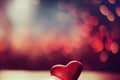 a red heart sitting on top of a white cupcake on a table next to a blurry background.