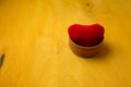 Red heart soft toy in wooden bowl on bright yellow background, copy space. valentines day love symbol, small souvenir, decor