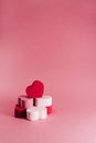 A red heart of sponge is on a pile of little hearts of sponges on a pink background. There are some heart of red, white and pink