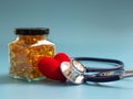 Red heart and stethoscope beside Fish oil capsules in glass bottles on blue background. Healthy omega-3 and stethoscope Royalty Free Stock Photo