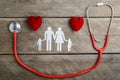 Red heart, stethoscope and paper chain family on wooden table Royalty Free Stock Photo