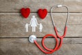 Red heart, stethoscope and paper chain family on wooden table Royalty Free Stock Photo