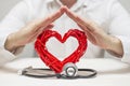 Red heart with stethoscope protected by man hands. Healthcare and medicine concept. Health insurance concept