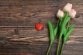 Red heart and three pink tulips on a brown wooden background. The concept of the holiday of Valentine`s Day, and International Royalty Free Stock Photo