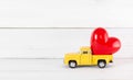 Red Heart on Toy Yellow Pickup Car on white wood background. Travel Love Concept with Copy Space Royalty Free Stock Photo