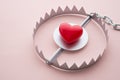 Red heart in a trap on pink background. Online internet romance scam concept. Love is bait or victim Royalty Free Stock Photo