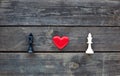Red heart between two chess kings on rustic wood