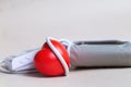 Red heart and white electronic tonometer isolated on beige background