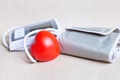 Red heart and white electronic tonometer isolated on beige background