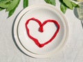 Red heart on white empty plate top-view close-up. Love concept. St. Valentine`s Day. Love proposal. Engagement. Restaurant.