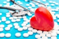 Red heart with white pills and stethoscope on blue. Medical background Royalty Free Stock Photo