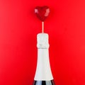 Red heart and white sparkling wine bottle on red background Royalty Free Stock Photo