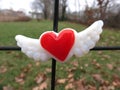 Red heart with wings magnet centered on metal fence. Royalty Free Stock Photo