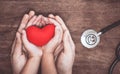 Red heart on woman and child hands and with doctor`s stethoscope