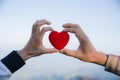 Red heart in woman and man hands, hands holding a soft heart shape, Couple love, Valentine`s Day