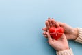 red heart in women`s hands on a blue background. The concept of health, donation, volunteering and health insurance.