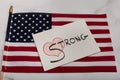 Red heart with the word strong painted on canvas sign sitting on an American flag