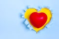 Red heart on Yellow Heart shape hole through blue paper Flat lay Happy Valentines day concept