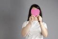 Red heart. A young, beautiful girl holds a heart in her hand, covering her face. Love concept. St. Valentine`s Day. Mercy and care Royalty Free Stock Photo