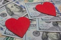 Red hearts on a background of dollar banknotes. Money love