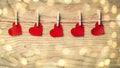 red hearts on clothespins on wooden background. beautiful bokeh effect from a garland. Royalty Free Stock Photo
