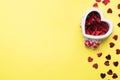 Red hearts confetti in a ceramic stand in the shape of a heart on a yellow background. Holiday card for Valentine`s Day. Flat lay Royalty Free Stock Photo