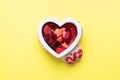 Red hearts confetti in a ceramic stand in the shape of a heart on a yellow background. Holiday card for Valentine`s Day. Flat lay Royalty Free Stock Photo