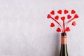 Red hearts pouring from wine bottle on gray background, copy space