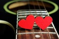 Red hearts on the strings of a guitar. Hearts are a symbol of love. Valentine`s Day