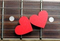 Red hearts on the strings of a guitar. Hearts are a symbol of love.