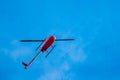 Red helicopter in flight on a blue sky, sunny day. Rotary. wing aircraft. Royalty Free Stock Photo