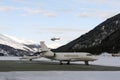 A red helicopter flying over two private jets in the airport of St Moritz Switzerland in winter Royalty Free Stock Photo