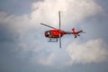 Red helicopter with propeller and blades is in the blue sky with clouds background Royalty Free Stock Photo