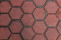 Red hexagonal paving tiles form a pattern on a sidewalk surface