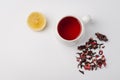 red hibiscus tea in a white mug, lemon segment and dry blossom isolated on white background. Top view and copyspace