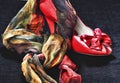 Red high heel and silk scarf on black backdrop