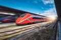 Red high speed train in motion on the railway station at sunset Royalty Free Stock Photo