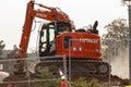 a red Hitachi excavator behind the fences at a dusty construction site